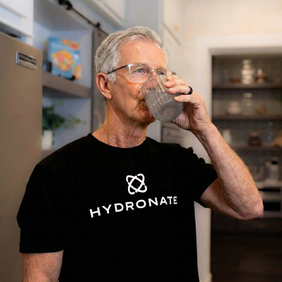 Hydronate customer drinking a glass of Hydronate water in his kitchen