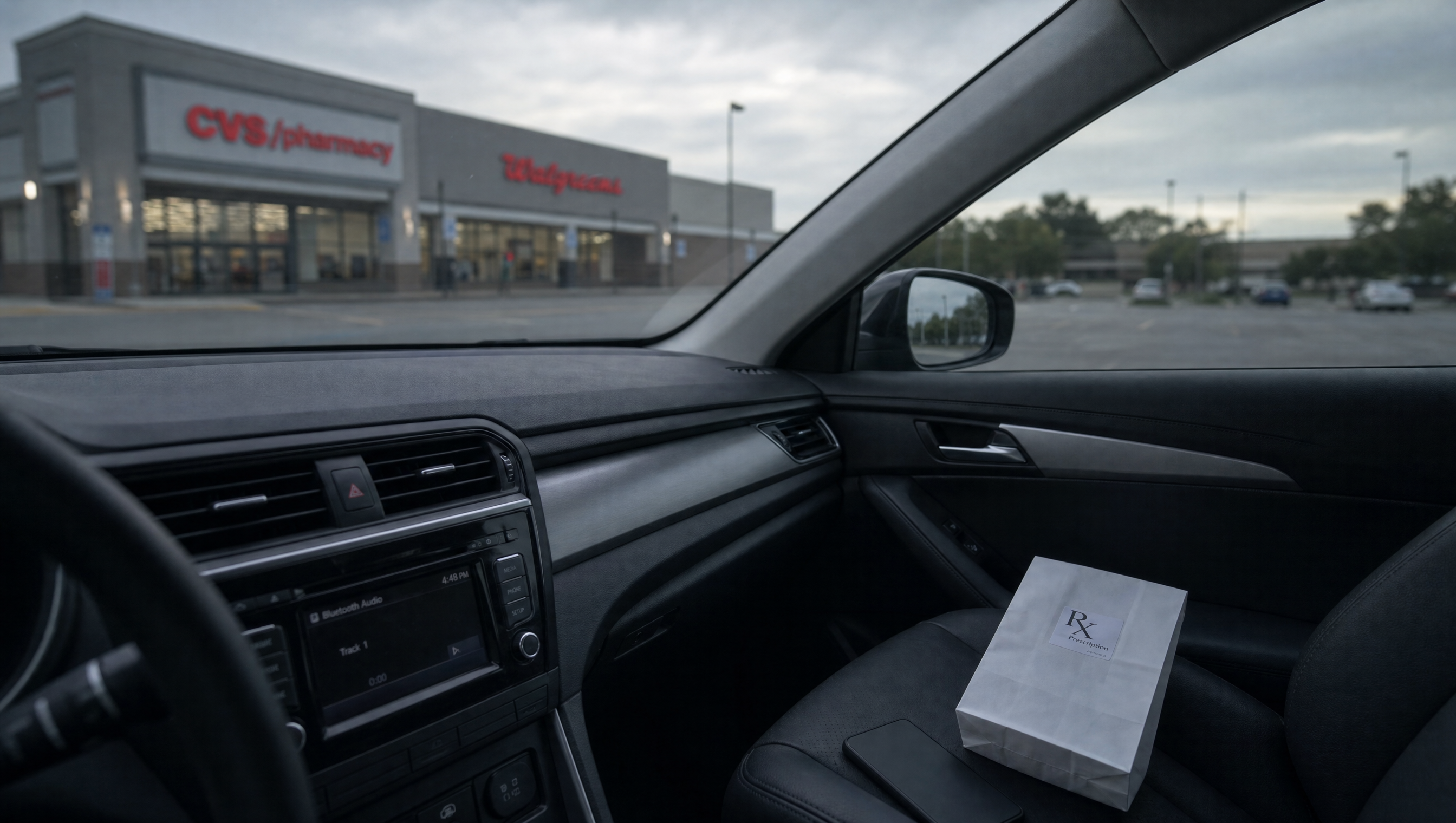 First-person view from the driver's seat of a parked sedan. The dashboard clock reads 4:48 PM. A white Rx prescription bag and a face-down phone rest on the leather passenger seat. Through the windshield, a CVS/Walgreens storefront sits across an empty parking lot under flat overcast late-afternoon light.
