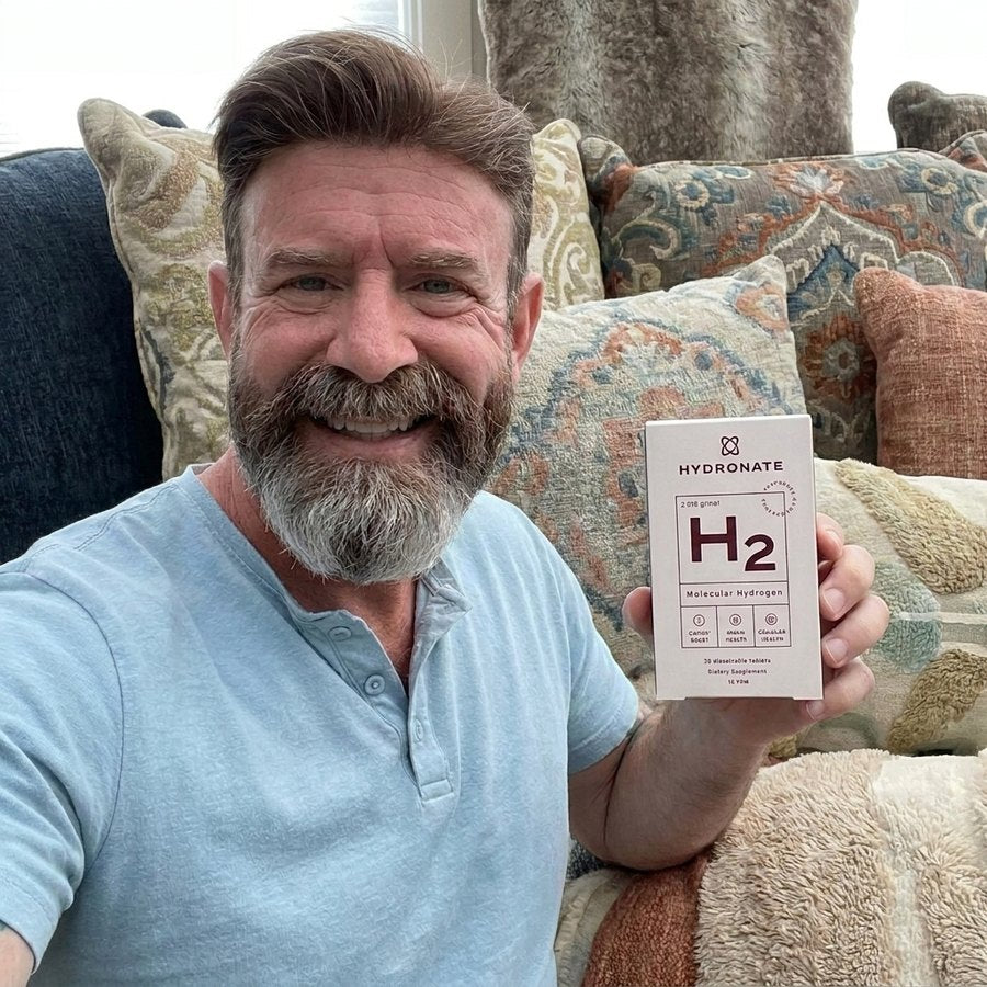 Customer holding a Hydronate H2 box on a patterned sofa.